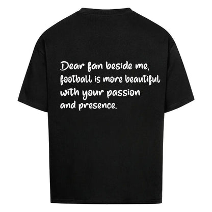 Football Oversized Shirt: Schwarzes Oversized-T-Shirt mit weißem Rückendruck: „Dear fan beside me, football is more beautiful with your passion and presence.“
