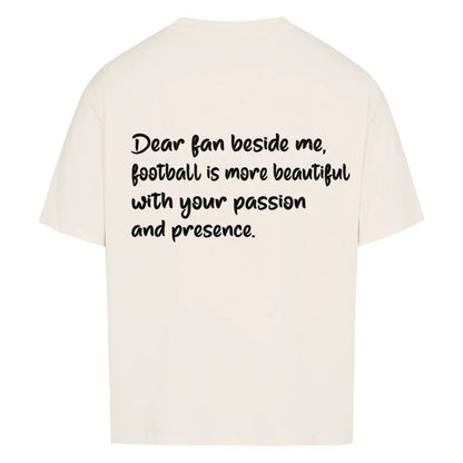 Football Oversized Shirt: Beiges Oversized-T-Shirt mit großem schwarzen Rückendruck: „Dear fan beside me, football is more beautiful with your passion and presence.“