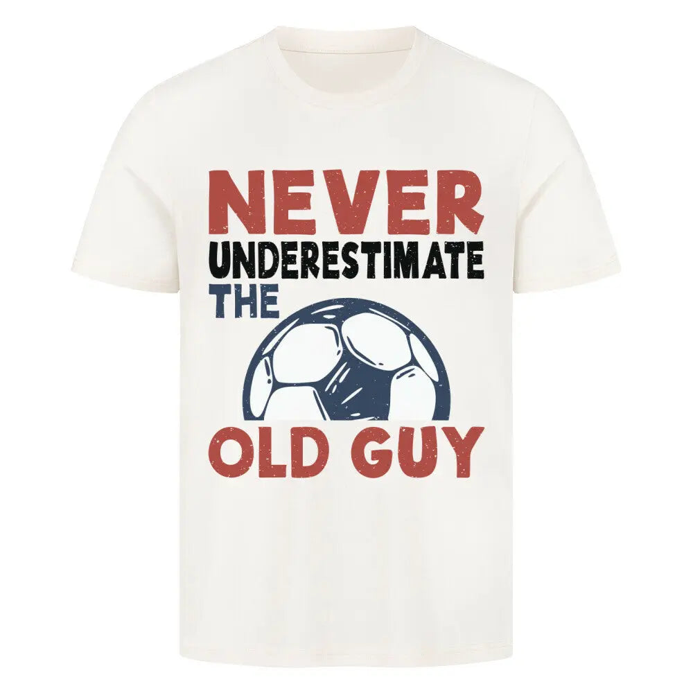 Premium T-shirts Never Underestimate the Old Guy: Naturfarbenes T-Shirt mit Retro-Design: Text „Never underestimate the old guy“ in Rot, Schwarz und Blau, kombiniert mit Fußball-Grafik